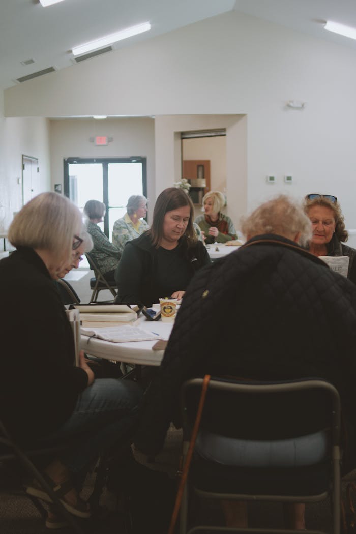 A diverse group of women gathered indoors for a Bible study session, focusing on community and faith.